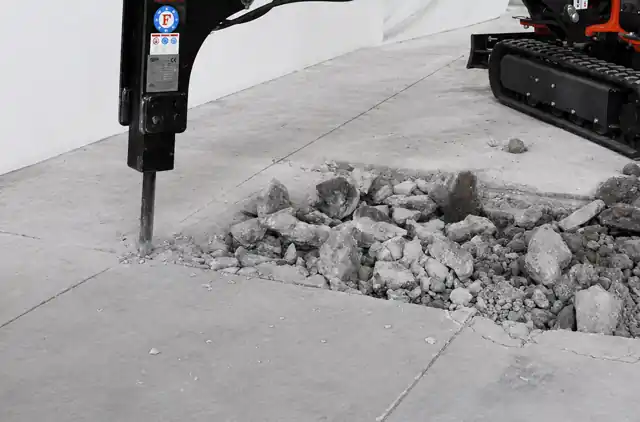 Mini-pelle équipée d’un BRH cassant une dalle béton